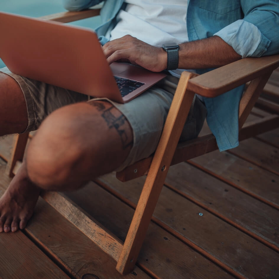 Homme travaillant sur ordinateur portable en terrasse bois