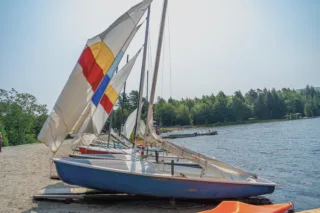 Small sailboats lined up on lakeshore beach