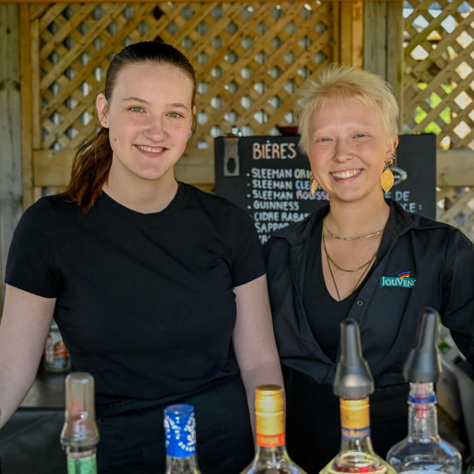 Deux barmaids souriantes derrière un comptoir de bar