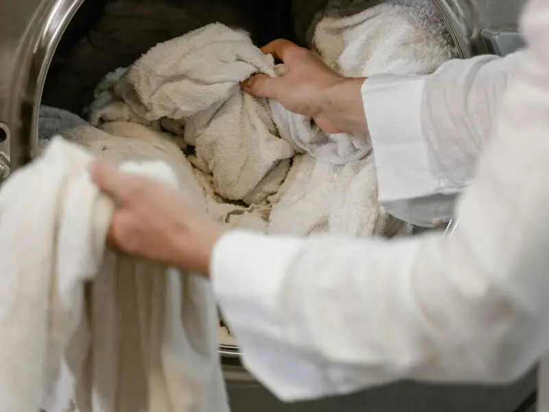 Personne chargeant serviettes blanches dans machine à laver