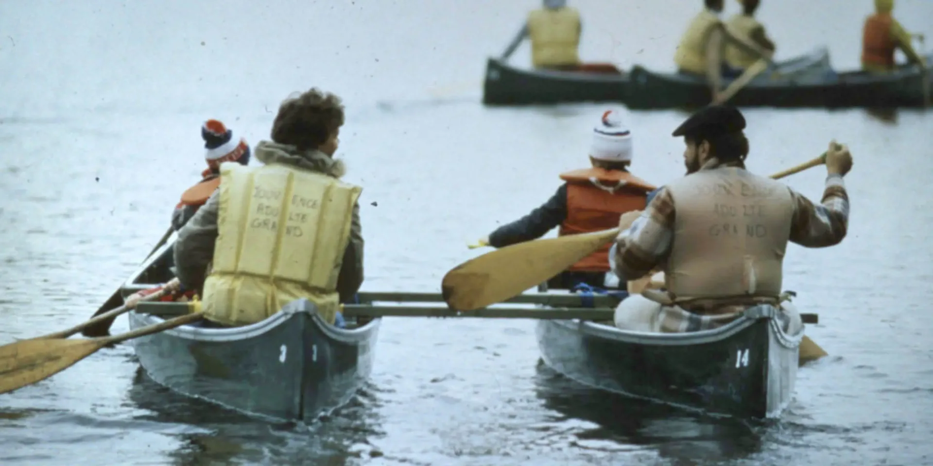 People canoeing on lake wearing life jackets