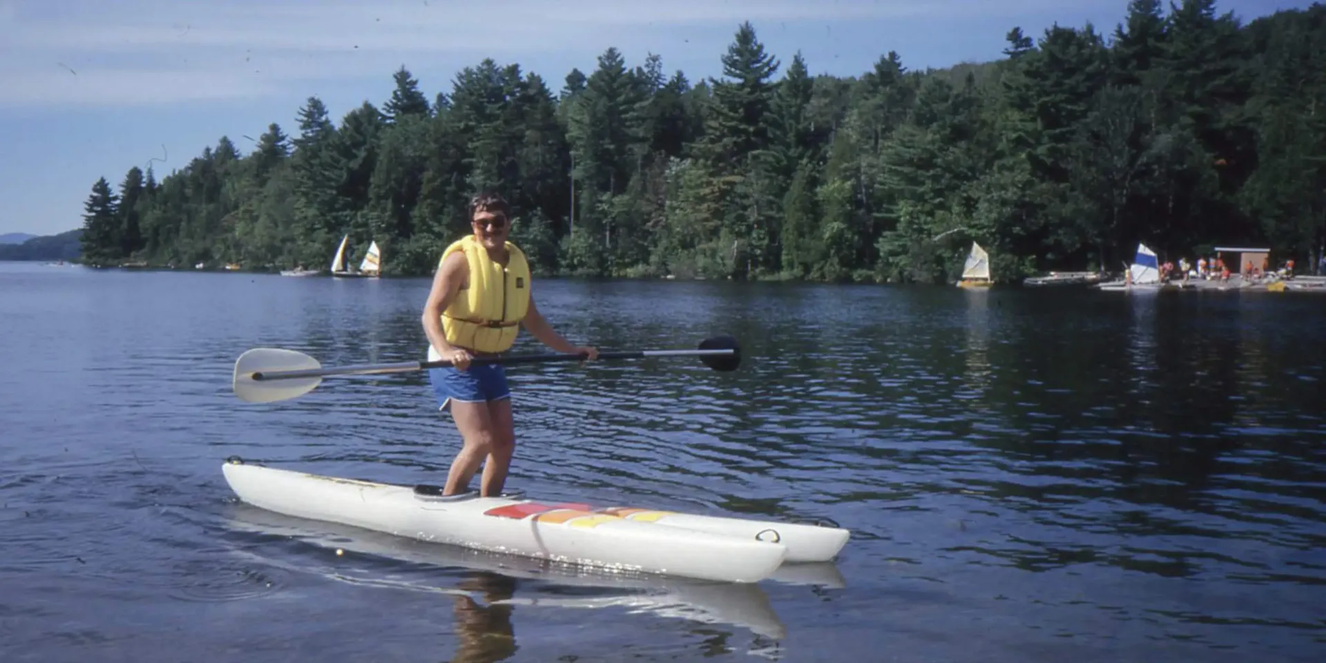 Person paddleboarding on lake with forested shoreline
