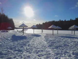 Plage enneigée avec abris en bois au soleil