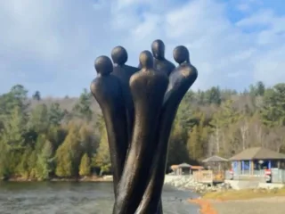 Sculpture abstraite de cinq silhouettes près d’un lac