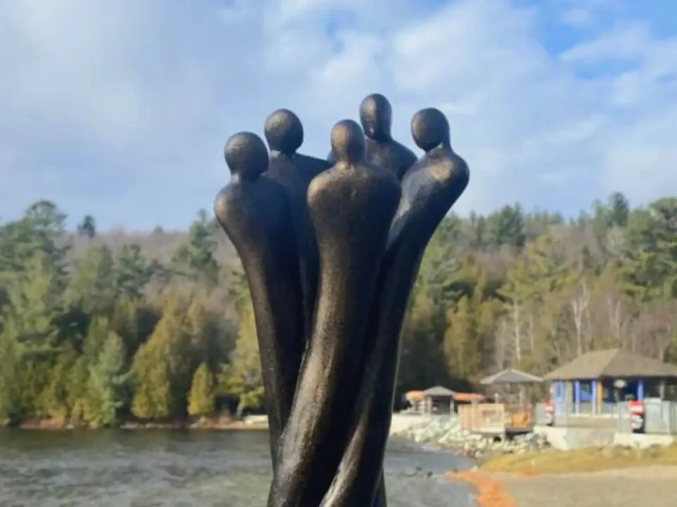 Sculpture abstraite de cinq silhouettes près d’un lac